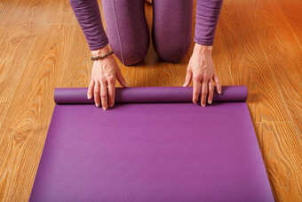 女人了淡紫色瑜伽席木地板上