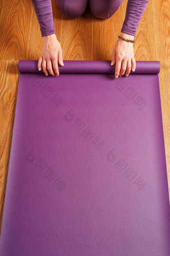 女人了淡紫色瑜伽席木地板上