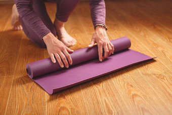 女人的手躺淡<strong>紫色瑜伽</strong>健身席锻炼实践首页木地板上