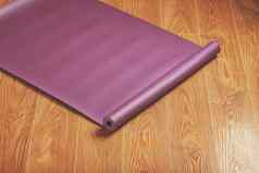 紫色的瑜伽健身席木地板上