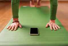 女人手表瑜伽类智能手机坐着绿色锻炼席