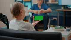上了年纪的女人持有水平绿色屏幕智能手机