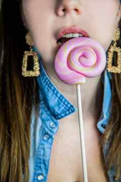 肖像美丽的女孩色彩斑斓的粉红色的旋转的东西棒棒糖硬糖果蓝色的背景糖果糖不健康的食物概念