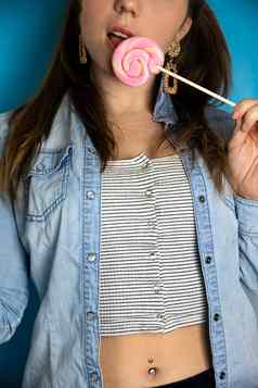 肖像美丽的女孩色彩斑斓的粉红色的旋转的东西棒棒糖硬糖果蓝色的背景糖果糖不健康的食物概念
