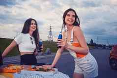 年轻的女士们微笑享受苏打水玻璃瓶摆姿势倾斜树干黄色的车披萨法国薯条关闭模拟