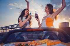 年轻的女孩微笑欢呼苏打水玻璃瓶摆姿势黄色的车Cabrio法国薯条披萨树干快食物复制空间