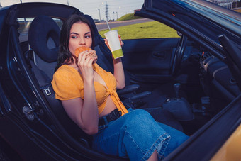 模型蓝色的牛仔裤橙色前吃汉堡持有<strong>饮料纸杯</strong>坐着黄色的车蓬式汽车快食物复制空间