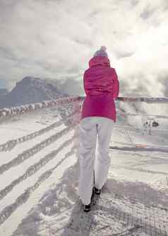 女人粉红色的滑雪夹克倾斜雪覆盖铁路滑雪跑道太阳云背光背景