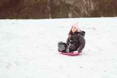 活跃的女孩滑动山快乐孩子有趣的在户外冬天雪橇家庭时间