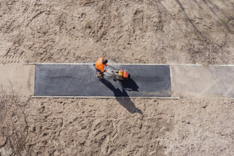 沥青建设工人铺设路表面人行道工作停机坪上人行道上建设路地面工作沥青奠定基础沥青铺平道路路工人振动板压实机框架
