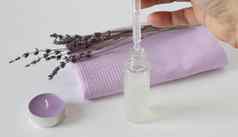 嫩枝干薰衣草芳香薰衣草蜡烛淡紫色毛巾瓶点眼药器白色背景概念和谐概念芳香疗法