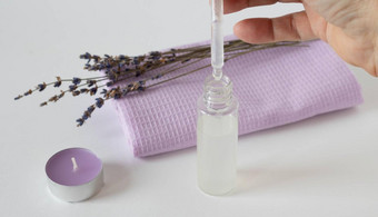 嫩枝干薰衣草芳香薰衣草蜡烛淡紫色毛巾瓶点眼药器白色背景概念和谐概念芳香疗法