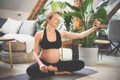 年轻的快乐快乐的美丽的怀孕了女人采取自拍移动电话住适合运动活跃的孕妇离开母亲怀孕瑜伽概念