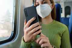 火车乘客智能手机应用程序旅行上下班穿保护脸面具焦点电话