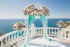 优雅的婚礼拱新鲜的花花瓶背景海洋蓝色的天空