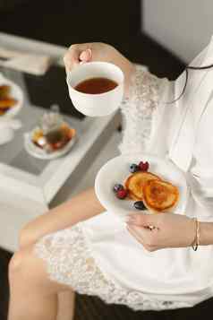 早....新娘女人持有杯子茶煎饼浆果