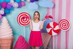 肖像快乐的年轻的女人粉红色的衣服背景装饰巨大的糖果冰奶油选择红色的鞋子