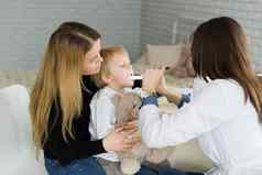 医生检查孩子的喉咙男孩妈妈。儿科医生办公室