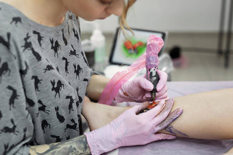 专业纹身艺术家使纹身腿年轻的女孩手纹身艺术家文身的人使纹身