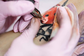 特写镜头纹身艺术家纹身腿年轻的女孩沙龙专业文身的人纹身工作室