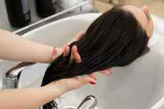 特写镜头手理发师按摩保湿石油客户的头发理发师适用于治疗面具女孩的头发