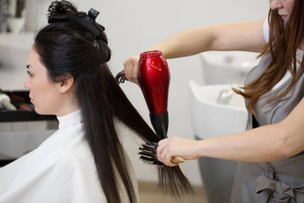 头发设计师工作女人发型沙龙干燥长棕色（的）头发头发干燥机轮刷