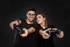美丽的年轻的夫妇玩视频游戏操纵 杆孤立的黑色的背景