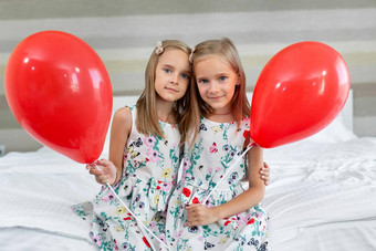 双胞胎姐妹美丽的礼服坐着床上酒店气球手