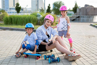妈妈。孩子们头盔坐滑板玩公园机器人车控制手套
