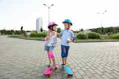 男孩头盔拥抱女孩公园骑滑板吃冰奶油