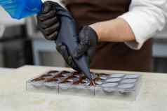 特写镜头巧克力的手倒巧克力模具酋长糕点袋倒热融化了巧克力硅胶模具