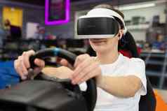 十几岁的男孩穿虚拟现实眼镜持有操舵轮戏剧电脑游戏控制台