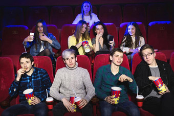 朋友坐电影看电影吃爆米花喝加气甜蜜的水电影娱乐概念