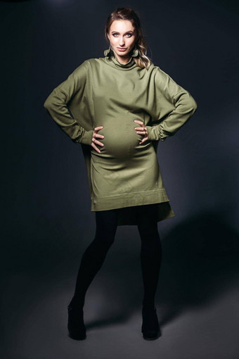 前面视图美丽的时尚怀孕了浅黑肤色的女人女人黑暗工作室漂亮的时尚的女人穿卡其色衣服持有怀孕了肚子相机概念怀孕