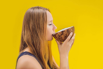 年轻的女人喝椰子牛奶查弗椰子黄色的背景