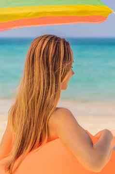 夏天生活方式肖像漂亮的女孩坐着橙色充气沙发海滩热带岛放松享受生活空气床上垂直格式新浪微博移动故事故事大小移动壁纸