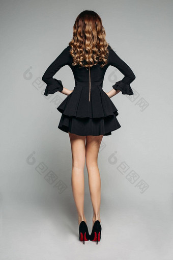 浅黑肤色的女人模型波浪头发摆姿势美丽的黑色的衣服挣扎裙子高高跟鞋