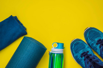 体育绿松石蓝色的阴影黄色的背景瑜伽席体育运动鞋子运动服装瓶水概念健康的生活方式体育运动饮食体育运动设备复制空间