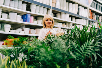 园艺种植购物概念美丽的成熟的成人女人选择室内植物锅温室花园中心高级购买花植物市场商店购物中心