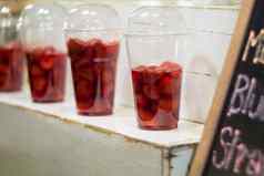 草莓糖浆塑料玻璃显示架子上准备使冰沙客户订单