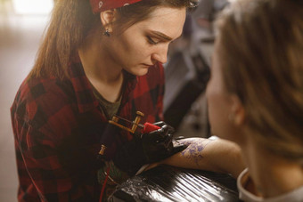 纹身艺术家穿保护手套开始画纹身客户端手臂