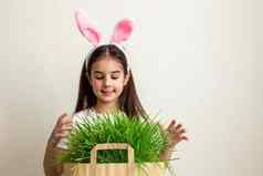 可爱的女孩粉红色的兔子耳朵持有纸袋草