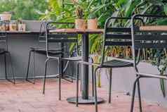 舒适的阳台阳台阳台开放空气热带风格咖啡馆金属椅子表格家具绿色自然叶子夏天一天现代装饰室内温暖的大气放松户外娱乐餐厅花园区域