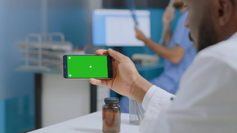 非洲美国治疗师医生持有模拟绿色屏幕浓度关键智能手机