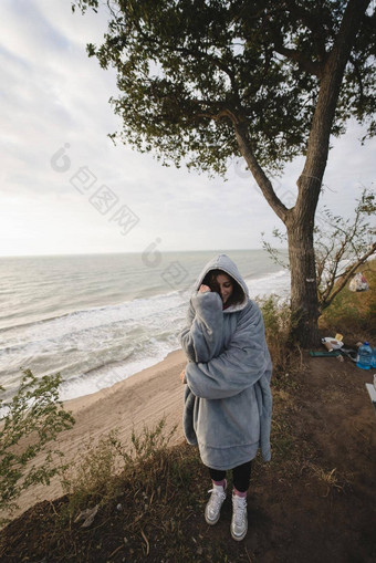 年轻的女人冷秋天海滨摆姿势相机