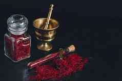生有机红色的干藏红花香料木背景古董金属黄铜砂浆杵玻璃Jar管