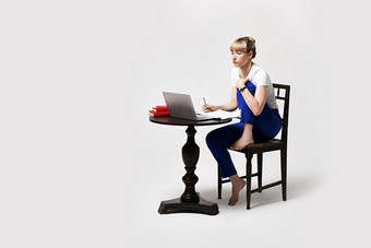 集中年轻的女人坐着桌子上工作研究远程在线写作笔记移动PC屏幕遥远的学习远程工作首页孤立的白色背景