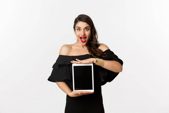 时尚购物概念惊讶年轻的女人显示在线网站<strong>促销</strong>提供平板电脑<strong>屏</strong>幕兴奋相机站黑色的衣服白色背景