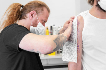 熟练的纹身艺术家把草图手臂男人。