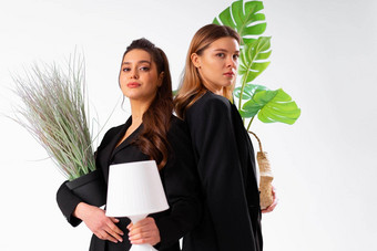 年轻的业务女人穿着黑色的西装微笑持有室内植物灯站孤立的白色背景移动概念搬迁办公室积极的
